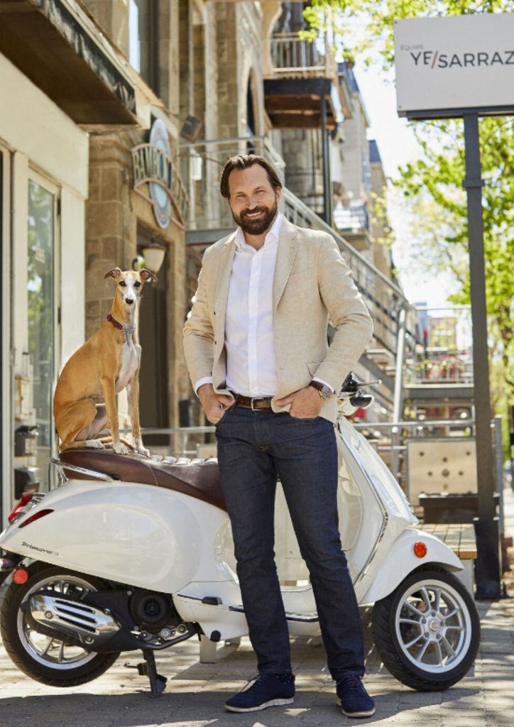 Yanick Sarrazin devant le bureau de l'agence YESARRAZIN, avec Bibi assise sur le scooter
